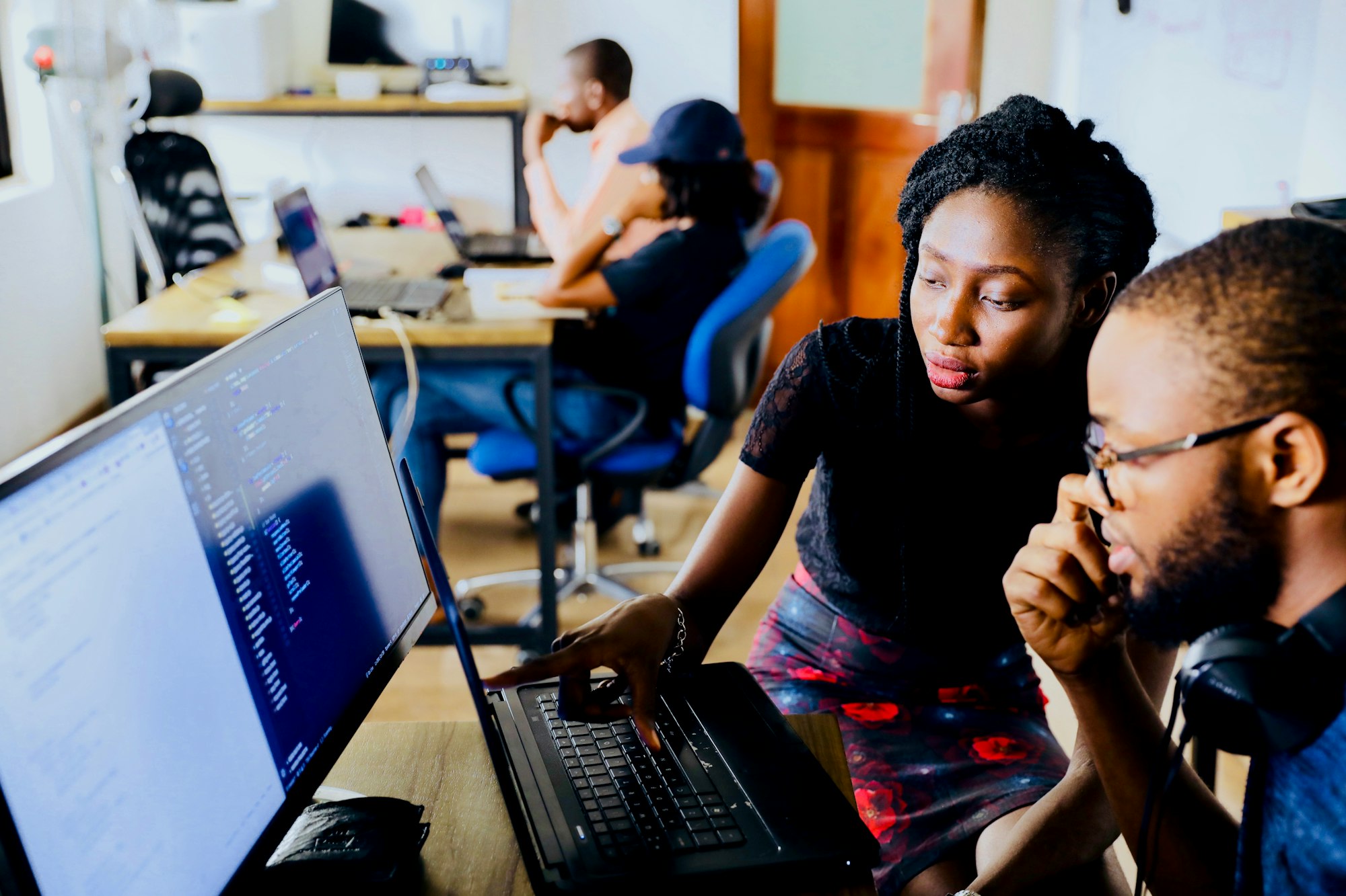Two people looking at a laptop screen together in a shared workspace.